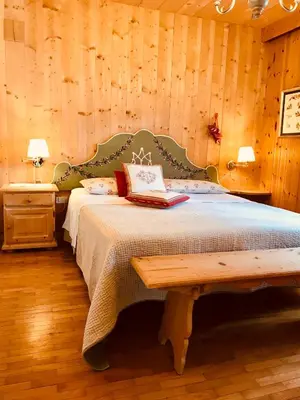 a bedroom with a bed with a wooden wall at B&B Pichler Casa in Castello di Fiemme