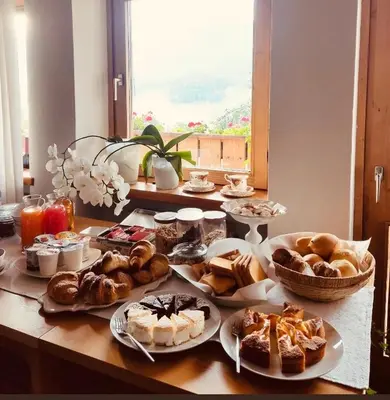 a table topped with plates of pastries and desserts at B&B Pichler Casa in Castello di Fiemme