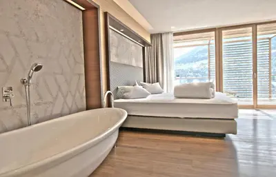 a bedroom with a tub and a bed with a window at B&B Boutique Hotel Burgund in Parcines