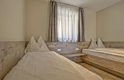 a bedroom with two beds and a window at B&B Boutique Hotel Burgund in Parcines