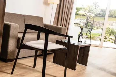 a black chair next to a couch and a side table at Hotel Thalhof am See in Caldaro