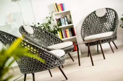 three wicker chairs and a table in a room at Hotel Thalhof am See in Caldaro