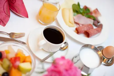 a table with a cup of coffee and a plate of fruit at Hotel Thalhof am See in Caldaro