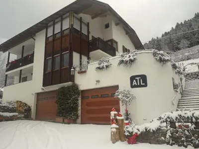 a house with a garage in the snow at ATL AGRITURISMO in Salorno sulla Strada del Vino