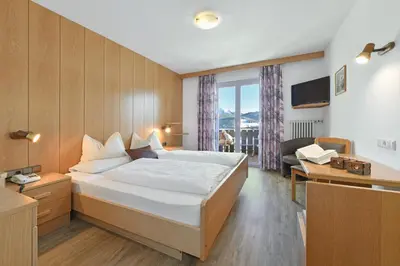 a bedroom with a bed and a desk and a couch at Panoramahotel Obkircher in Nova Ponente