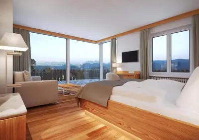 a bedroom with a large bed and large windows at Panoramahotel Obkircher in Nova Ponente
