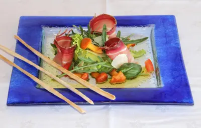 a blue plate of food on a table with chopsticks at Panoramahotel Obkircher in Nova Ponente