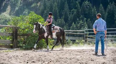 a woman is riding a horse while a man watches at Seebacher Apartments in Sarntal