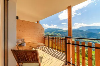 a balcony with a wooden bench and a view of mountains at Huberhof in Villandro