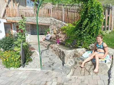 a young girl sitting on a rock wall in a garden at Huberhof in Villandro