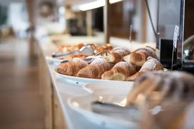 a buffet line with trays of pastries on at Familienhotel Maria in Obereggen