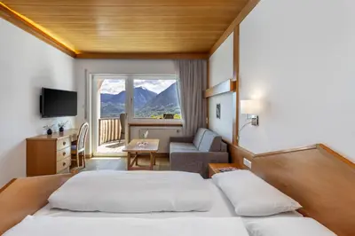 a hotel room with two beds and a couch at Hotel Panorama in Tirolo
