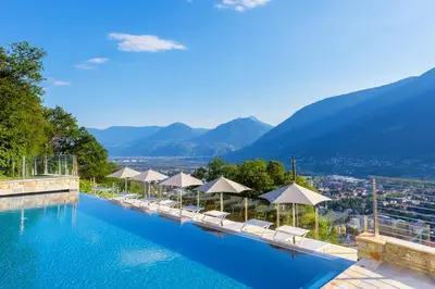 a large swimming pool with chairs and umbrellas at Hotel Panorama in Tirolo