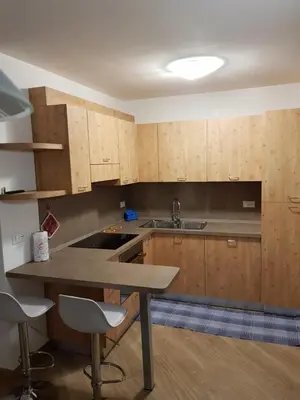 a kitchen with wooden cabinets and a table and chairs at Casa Alice 5.3 in Fiera di Primiero