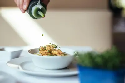 a person is sprinkling sauce on a bowl of food at Hotel Rablanderhof in Rablà