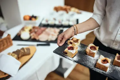 a person holding a tray of food on a table at Hotel Rablanderhof in Rablà