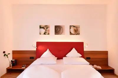 a bedroom with a bed with a red headboard at Hotel Rablanderhof in Rablà