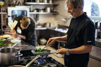 a man in a kitchen preparing food in a wok at Hotel Rablanderhof in Rablà