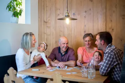 a group of people sitting around a table playing a game at Waidacherhof Apartments in Braies
