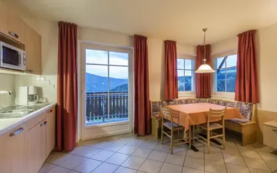 a kitchen with a table and a dining room with a view at Residence Treyer in Terento