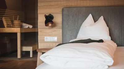 a bedroom with a bed with white pillows and a table at Hotel Solvie in Falzes