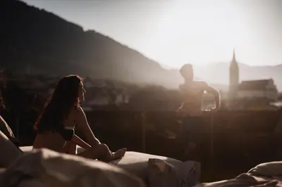 a woman sitting on a bed with a man in the background at Hotel Solvie in Falzes