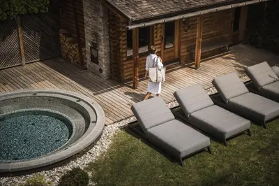 a person standing on a deck next to a pool at Hotel Lanerhof active/spa/balance in San Lorenzo di Sebato