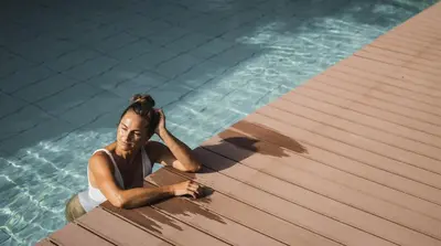 a woman in a swimming pool looking at her cell phone at Hotel Lanerhof active/spa/balance in San Lorenzo di Sebato