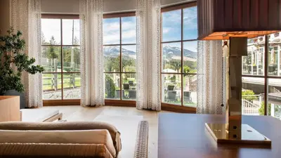 a living room with a table and large windows at Hotel Sonnalp in Obereggen