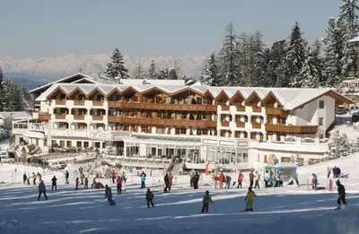 a group of people skiing in front of a ski lodge at Hotel Sonnalp in Obereggen