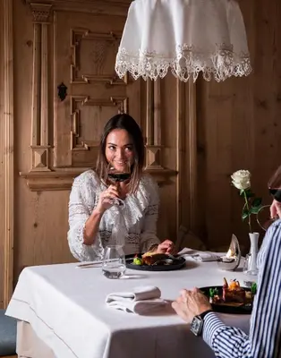 a woman sitting at a table with a glass of wine at Hotel Sonnalp in Obereggen