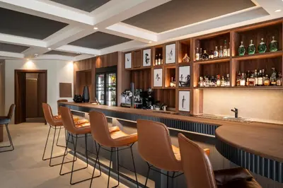a bar in a restaurant with a row of stools at Hotel Sonnalp in Obereggen