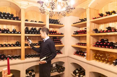 a man in a wine cellar holding a bottle of wine at Hotel Sonnalp in Obereggen