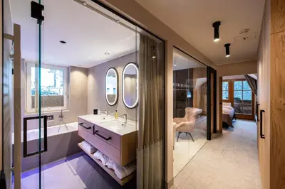 a bathroom with a tub and a sink and a mirror at Hotel Sonnalp in Obereggen