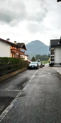 a parking lot with cars parked in front of a house at Apartment 18 Federico Bandi Cavalese in Cavalese
