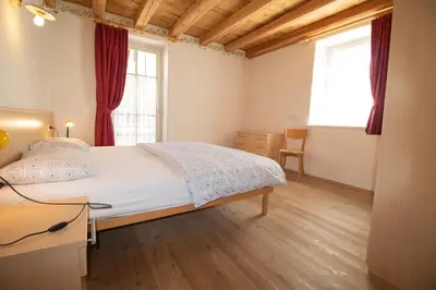 a bedroom with two beds and a chair at Casa Torta in Moena
