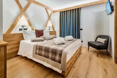 a bedroom with a large bed and a chair at Camina Suite and Spa in Cortina dʼAmpezzo