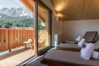 a room with two beds and a balcony with mountains at Camina Suite and Spa in Cortina dʼAmpezzo