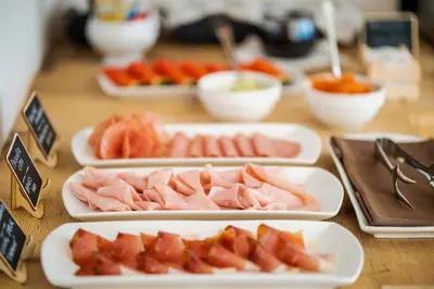 a table topped with plates of meat and fruit at Camina Suite and Spa in Cortina dʼAmpezzo