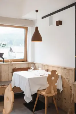 a dining room with a white table and a window at Camina Suite and Spa in Cortina dʼAmpezzo
