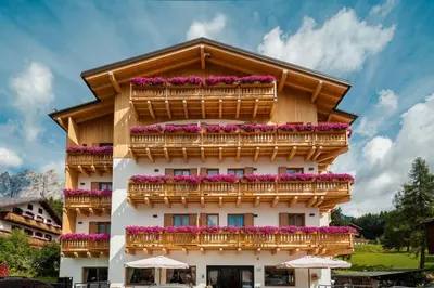 a building with flowers on the balconies at Camina Suite and Spa in Cortina dʼAmpezzo