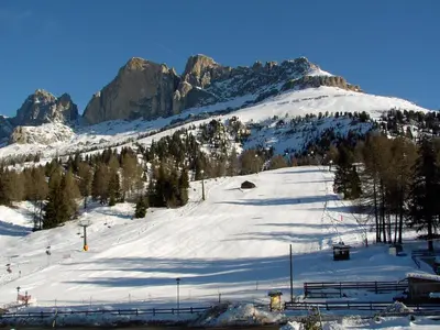 a snow covered slope with a mountain in the background at Hotel Castel Latemar in Carezza al Lago