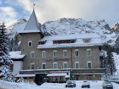 a large building with a snow covered mountain in the background at Hotel Castel Latemar in Carezza al Lago