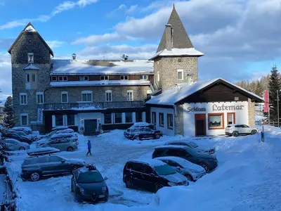 a large building with cars parked in the snow at Hotel Castel Latemar in Carezza al Lago