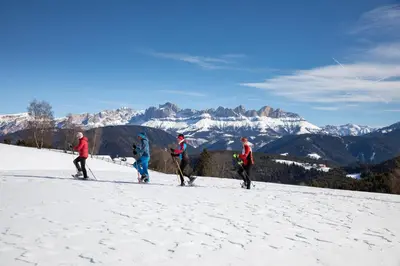 a group of people flying a kite on a snow covered mountain at Hotel Castel Latemar in Carezza al Lago