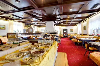 a restaurant with a long table with bowls of food at Hotel Castel Latemar in Carezza al Lago