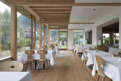 a restaurant with white tables and chairs and windows at Hotel Taufers in Molini di Tures