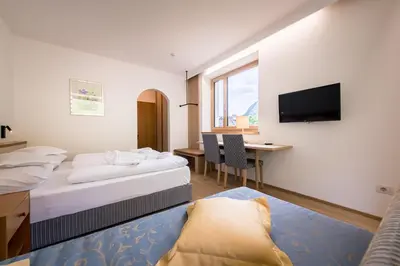 a hotel room with two beds and a desk and a television at Hotel Taufers in Molini di Tures