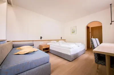 a hotel room with two beds and a couch at Hotel Taufers in Molini di Tures