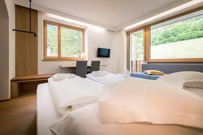 a room with four beds and a window at Hotel Taufers in Molini di Tures